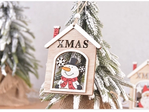 Detailed close-up of a wooden XMAS house ornament with a painted snowman on a snowy branch