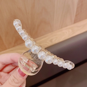 Detail of elegant pearl hair claw clip with transparent base and strong metal spring