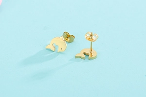 Macro detail of glossy golden dolphin stud earrings on a soft blue background