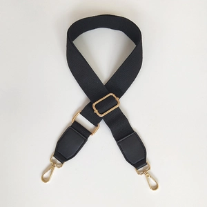 Detail of black adjustable canvas shoulder strap with gold metal lobster clasps and buckles