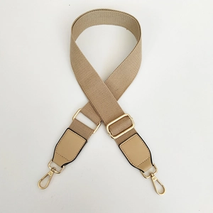 Detail of adjustable beige canvas strap with gold metal lobster hooks and leather ends