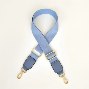 Close-up of sky blue canvas strap with golden metal hooks and leather ends for bags