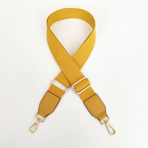 Detail of adjustable mustard yellow canvas strap with gold metal buckles and leather ends