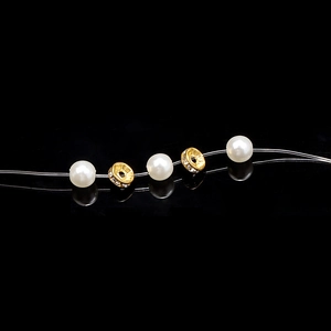 Detailed close-up of white pearls and gold crystal spacer beads on a black reflective surface