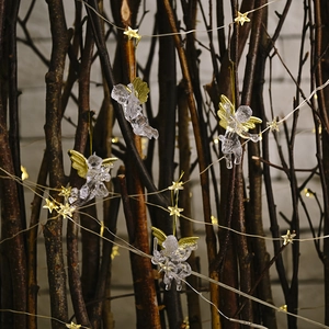 Transparent Christmas angel ornaments with gold wings hanging on lighted branches