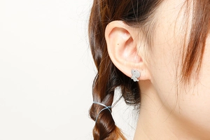 Détail d'une puce d'oreille chiot en argent portée avec une finition métal lisse