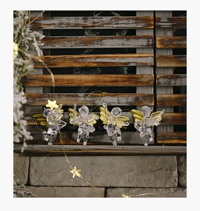 Clear acrylic Christmas angel ornaments with gold wings hanging by a cozy window