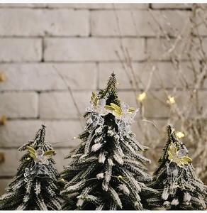 Detailed view of four transparent resin angels with gold wings on a snowy Christmas tree