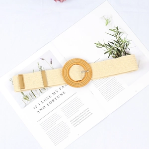 Détail d'une ceinture élastique tressée beige avec une boucle ronde en rotin sur fond neutre