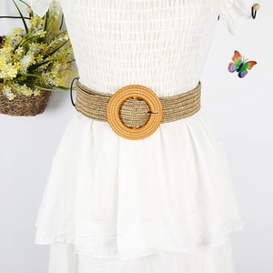 Detail of beige woven waist belt with a round orange straw buckle on a model