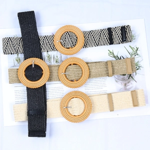 Flat lay of four woven straw belts featuring round wooden buckles in assorted neutral colors