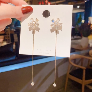 Macro detail of gold flower earrings with sparkling zircons and elegant long tassel drops