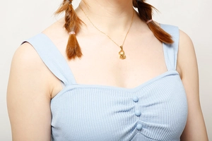 Gros plan d'un collier pendentif animal creux en acier titane doré sur un modèle