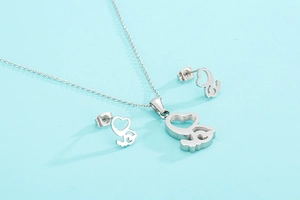 Vue détaillée d'un ensemble bijoux cœur et ange en acier argenté sur fond bleu clair