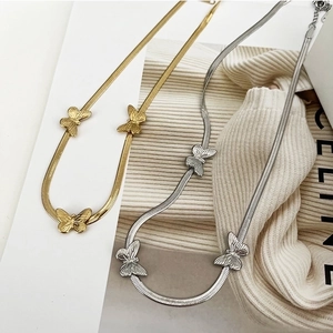 Flat butterfly necklaces in gold and silver steel on minimalist chic background