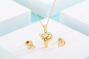 Detailed view of golden hollow fox necklace and stud earrings set on minimalist props
