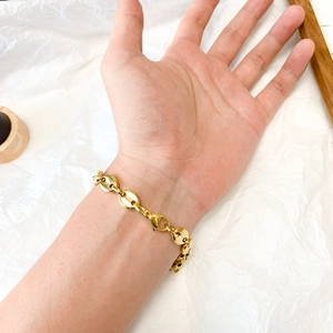 Detail shot of a men's gold coffee bean link bracelet worn on wrist with metal luster