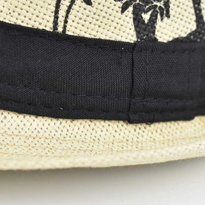 Detail of linen sun hat showing braided texture, black ribbon, and palm tree print