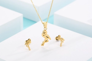 Macro shot of gold flamingo pendant necklace and stud earrings set on a clean blue background