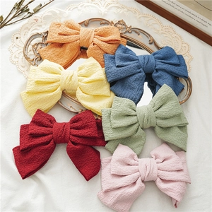 Detailed close-up of colorful oversized layered bow hair clips with textured seersucker fabric
