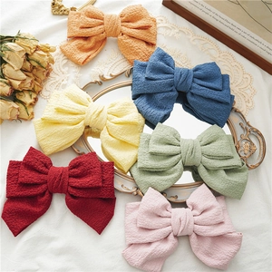 Detailed collection of 6 colorful pleated ribbon bow hair clips on a vintage mirror