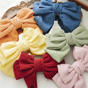 Detail of six layered bow hair clips in assorted colors on a vintage decorative tray