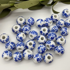 Detailed view of round white porcelain beads with blue floral patterns and large holes