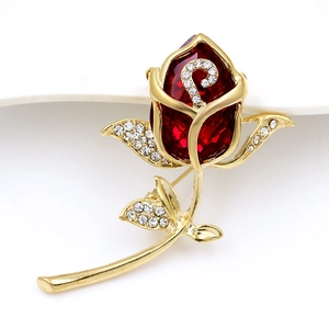 Detailed close-up of rose brooch with red faceted crystal and sparkling rhinestones