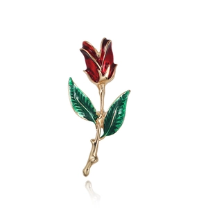 Detail of red enamel rose brooch with green leaves and gold stem on white background
