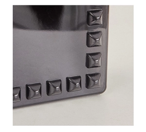 Macro shot of dark grey PVC tote bag featuring metallic pyramid stud edge detailing