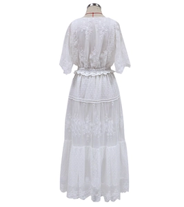 Detailed back view of white lace dress with embroidery and layered skirt on mannequin