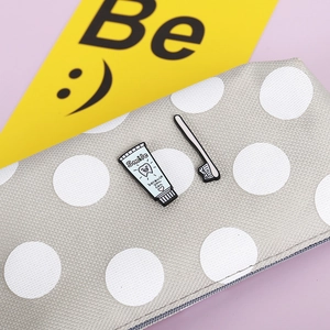 Detail of toothpaste and toothbrush enamel pins on a polka dot bag with cute smile slogan