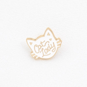 Detail of white enamel cat brooch with gold metal edges and Cat Lady text engraving