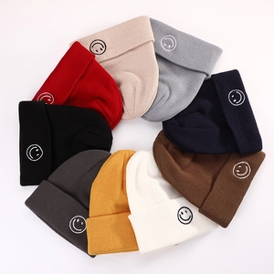 Set of 9 colorful knitted beanies with smiley face embroidery on a clean white background