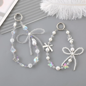 Detail of beaded phone charms with laser beads, pearls, and bows on a feather background