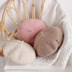 Detailed close-up of pink, beige, and brown wool berets with elegant pearl decorations