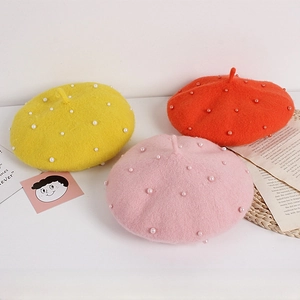 Detail view of colorful wool felt girls' berets featuring white pearl decorations