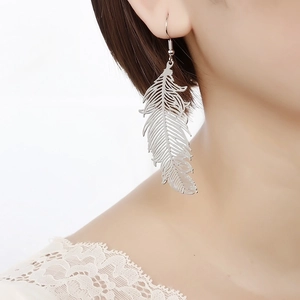 Elegant silver hollowed-out feather drop earrings shown on a model for jewelry display