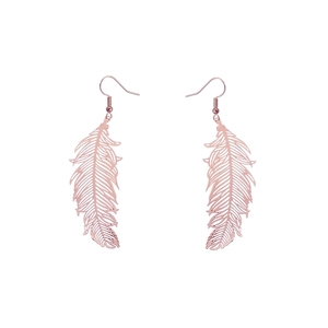 Macro shot of rose gold feather earrings with detailed hollow metal carving texture