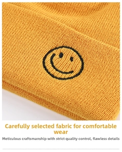 Detail of yellow ribbed knit beanie featuring black embroidered smiley face on the cuff