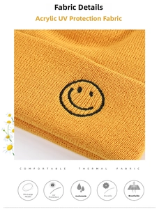 Close-up detail of yellow knit beanie featuring black embroidered smiley face and ribbed texture