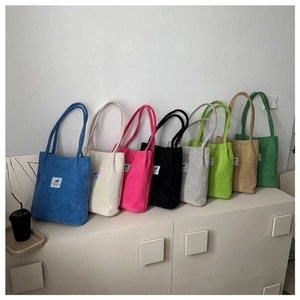Detailed display of eight colorful corduroy tote bags lined up on a white shelf