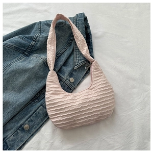 Detail of pink dumpling bag with cloud-like pleated texture on denim jacket