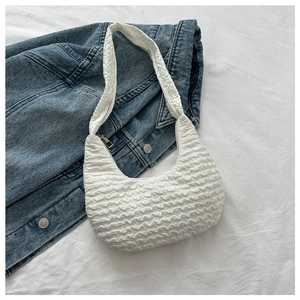 White textured crescent shoulder bag styled over a blue denim jacket background