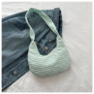 Detail of mint green pleated crescent shoulder bag styled on a blue denim jacket