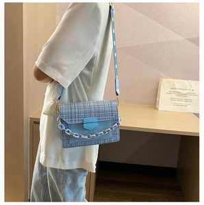 Blue tweed crossbody bag with floral strap and leather flap shown on a model
