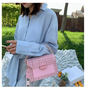 Pink tweed crossbody bag with gold chain and sunflower strap in outdoor picnic setting