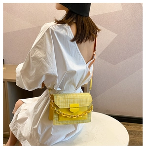 Detail of yellow woven texture and matching chain on a crossbody small square bag