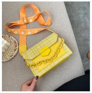 Detail of yellow woven texture crossbody bag with resin chain and daisy print strap