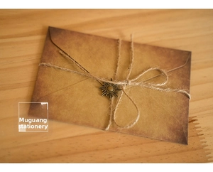 Vintage kraft paper envelope with jute twine and bronze sun pendant on wooden table